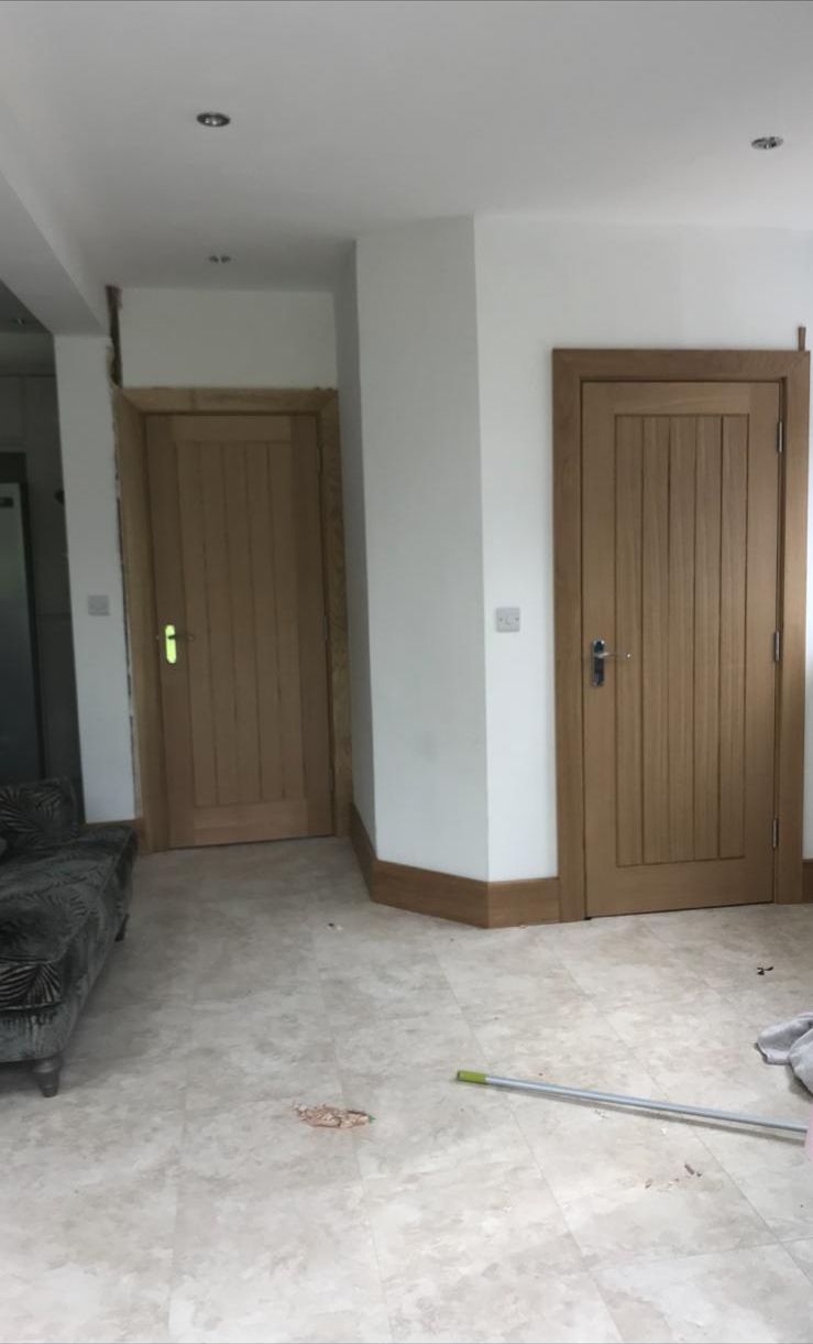 Two oak internal doors with matching frames in a new-build hallway