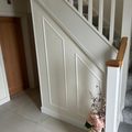 Staircase side wall finished in white panelling, white spindles and an oak handrail cap, grey tiled hallway floor